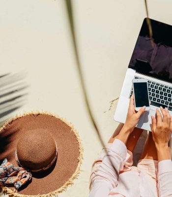 seccion-media-de-una-mujer-usando-una-computadora-portatil-y-un-telefono-en-la-playa